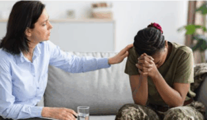 Millitary woman on sofa with counsellor comforting with hand on her shoulder.